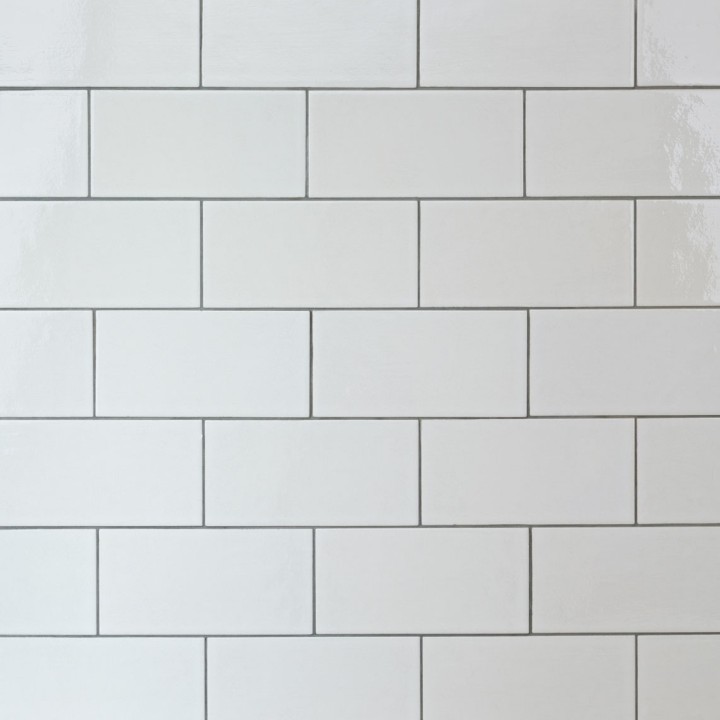 Wall of chalk white large metro tile finished with medium grey grout laid in a brick bond pattern