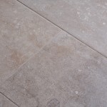 Close up of warm stone effect porcelain floor tile with Beige grout at an angle
