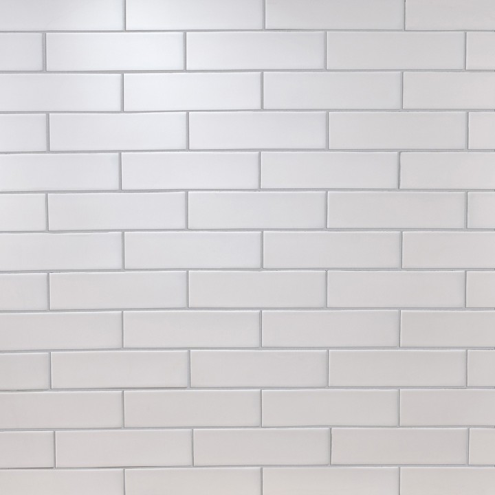 Wall of sky white skinny metro matt tiles with silver grey grout laid in a brick pond tile pattern