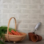 Wall of gloss neutral green medium metro tile laid in a brick bond tile pattern behind gardening accessories
