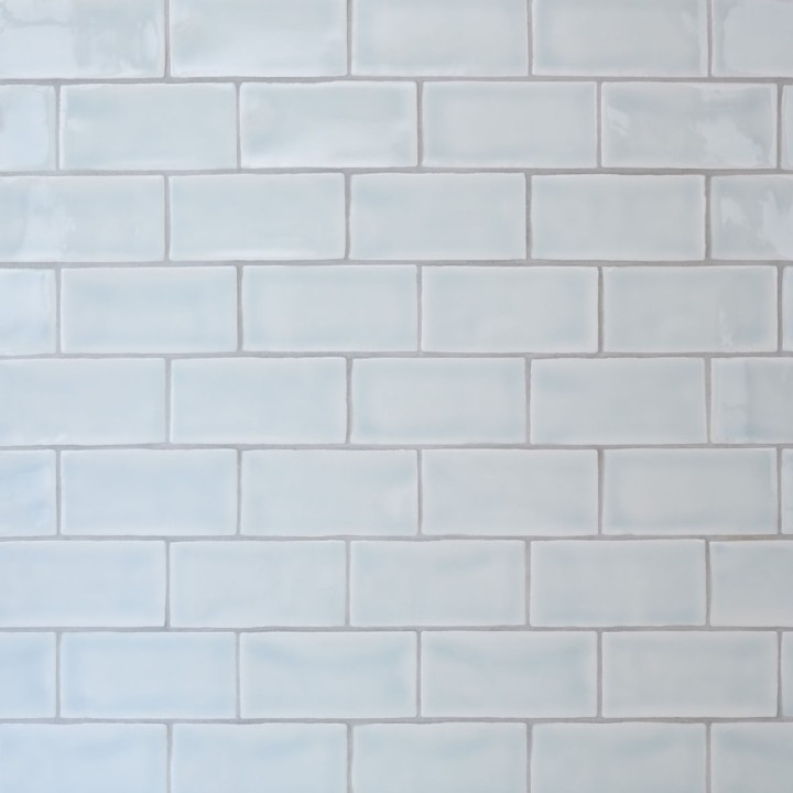 Wall of gloss neutral cool white metro tile laid in a brick bond tile pattern finished with silver grey grout