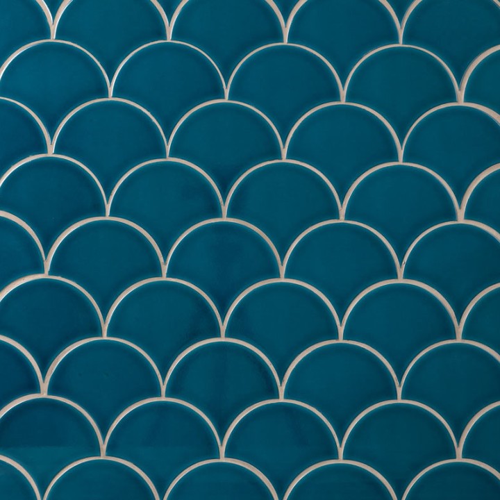 Wall of teal scallop tiles with white grout laid in a fish scale pattern ideal for kitchens and bathrooms