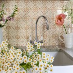 Belfast sink filled with daisies in front of a wall of Mediterranean burnt orange handpainted wall tiles