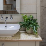 Vanity sink filled with amber yellow Mediterranean tiles underneath a sink against a paneled wall