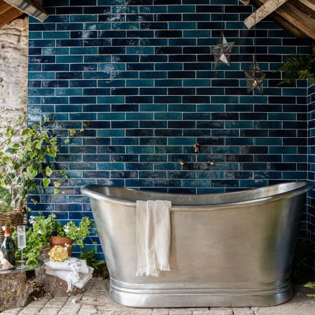Isles Islay skinny metro wall tiles on wall behind silver tin bath in outdoor bathroom