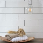 Wall of chalk white large metro tile finished with medium grey grout behind bathroom accessories against an oak work top