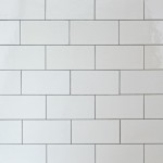 Wall of chalk white large metro tile finished with medium grey grout laid in a brick bond pattern
