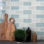 Wall of pastel green and blue metro tiles behind a chopping board and kitchen accessories