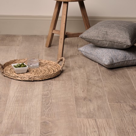 Wood effect floor laid in a straight pattern against cream wall with a stool and wicker tray