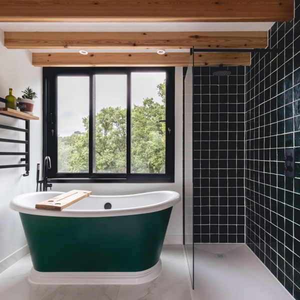 Master bathroom suite with victorian green square tiles in the shower and a free standing green bath.