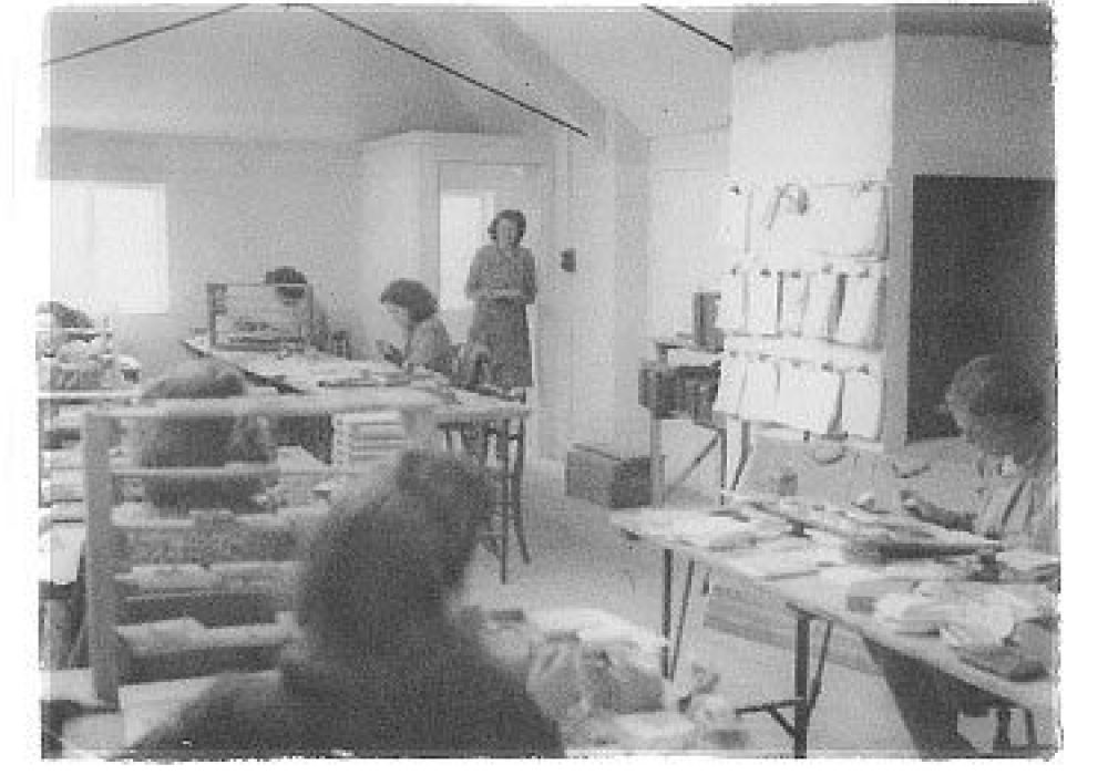 Black and white photo of a tile factory with four females hand painting wall tiles.