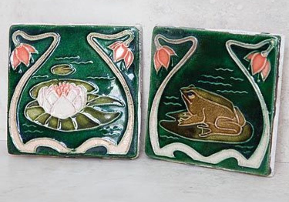 Two hand painted tiles of a lotus leaf and a frog on a green tile with a pink flower border.