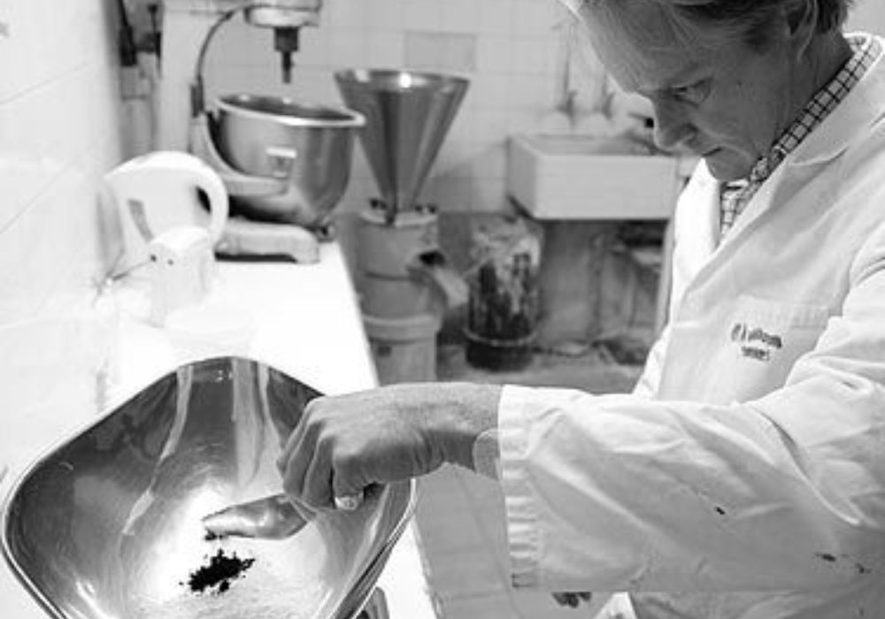 Black and white image of our MD Jamie Robb weighing paint pigments in our tile lab.