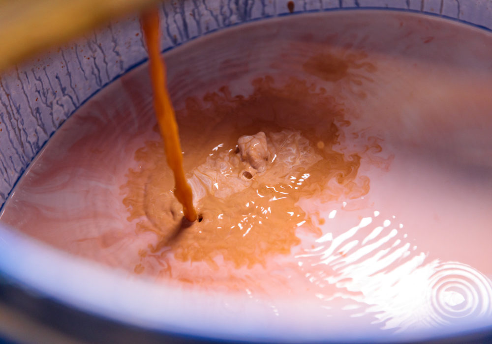 Close up of an orange glaze being poured into a barrel