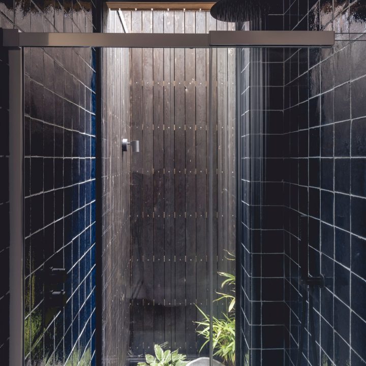 Statement shower tiled with navy square tiles framing a floor to ceiling window