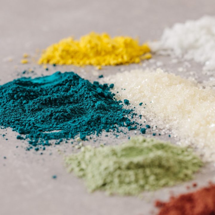 Close up image of four colour pigments of turquoise, green, off-white and yellow