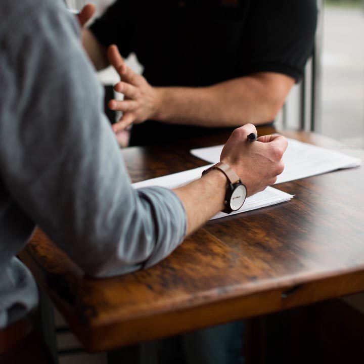 Close up of two individual's arms making notes from a meeting