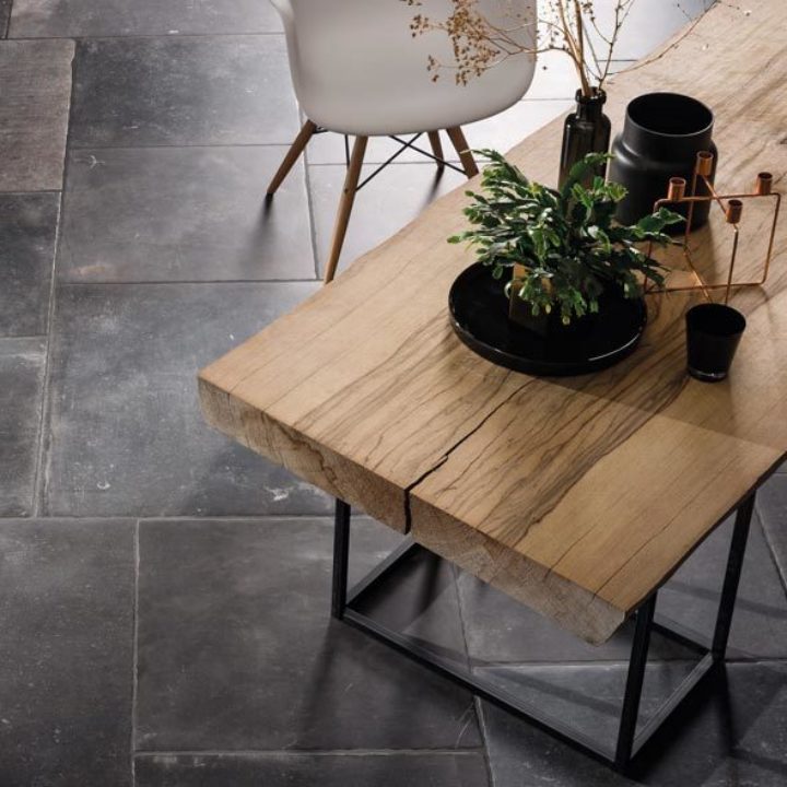 Birds eye view of a slate effect floor tile with a rustic dining table on top and decorated with flowers and vases.