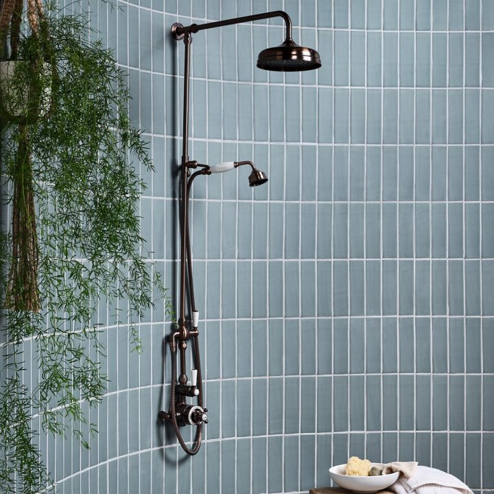 Curved shower tiled from floor to ceiling with teal skinny metro matt tiles with a chrome shower and rustic accessories