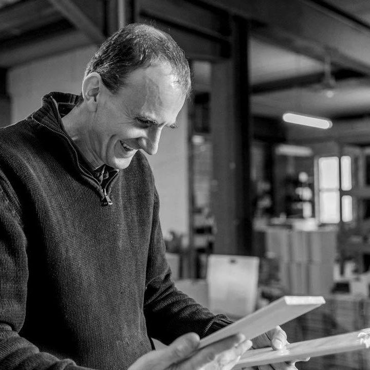 Black and white image of Paul holding two metro tiles that would have finished on the kiln.