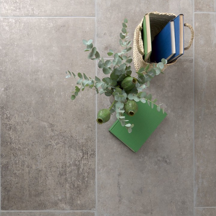Floor of rectangle warm taupe stone effect porcelain floor tiled with grey grout with home accessories on top