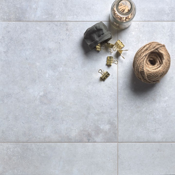 Floor of square cool grey stone effect porcelain floor tile with beige grout and yarn and accessories on top