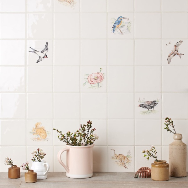 Wall of british wildlife animal square tiles, painted by hand against a wood worktop with vases in front