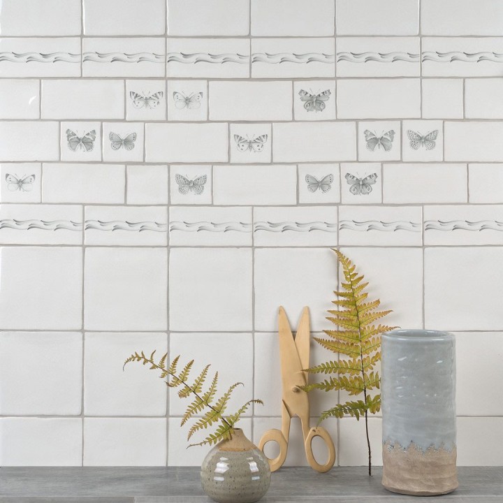 Wall of square antique white tiles paired with butterfly taco tiles and border metro tiles