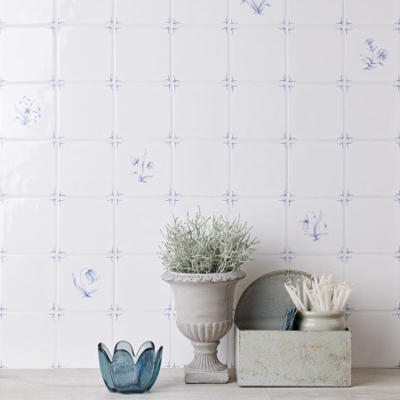 Wall of delft flower square tiles mixed with plain delft tiles in the classic blue style behind home accessories