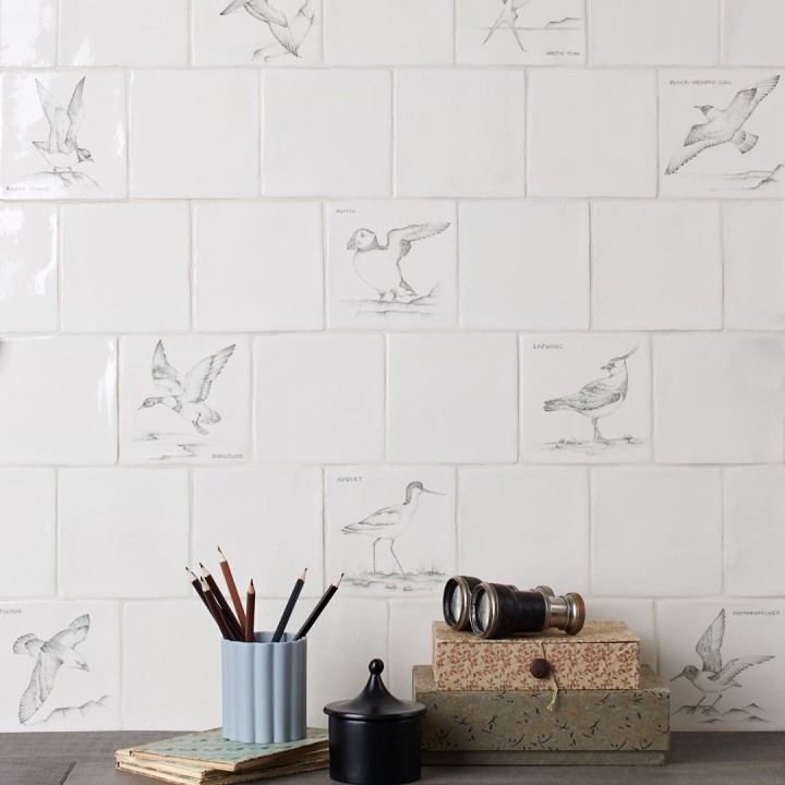 Wall of hand painted coastal bird square tiles in a charcoal style with an antique background paired with plain antique white tiles