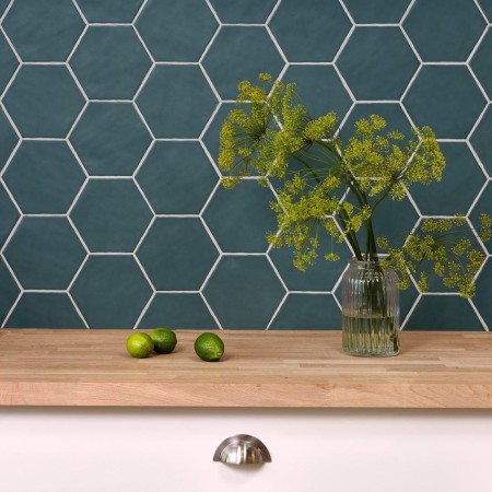 Wall of Latitude Dogger Hexagon tiles finished with white grout behind an oak work top and house plant