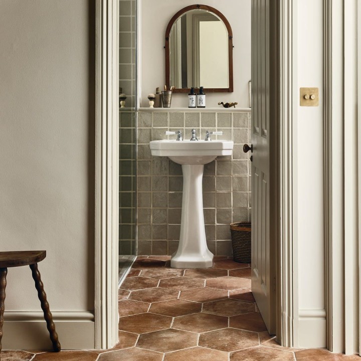 Terracotta Granada Hexagon tiles laid on a floor leading to a bathroom sink with green wall tiles