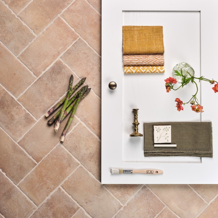 Flatlay of pale terracotta Seville Small Brick tiles laid in a herringbone pattern and finished with Limestone grout with Fermoie swatches and cupboard