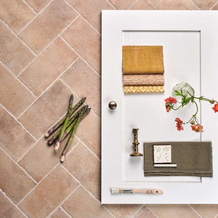 Flatlay of pale terracotta Seville Small Brick tiles laid in a herringbone pattern and finished with Limestone grout with Fermoie swatches and cupboard