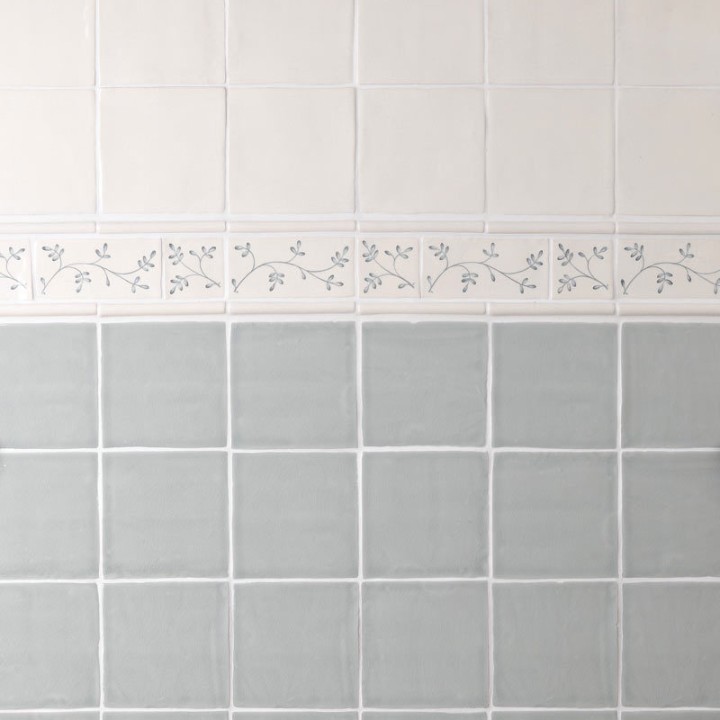 Wall of square tiled halfway with Emma flax blue pattern brick and taco tiles as a border, finished with half rounds.