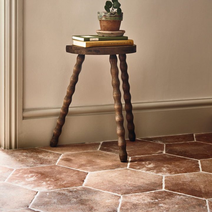 Terracotta Granada Hexagon tiles laid on a floor with a wooden stool on top