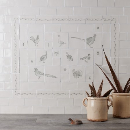 Cooker splash back tile panel with country birds and insects with a vase of aloe vera and oak work top.