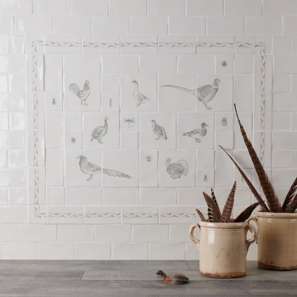 Cooker splash back tile panel with country birds and insects with a vase of aloe vera and oak work top.