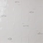 Wall of antique white tiles and fish tiles hand painted with fish motifs with white grout