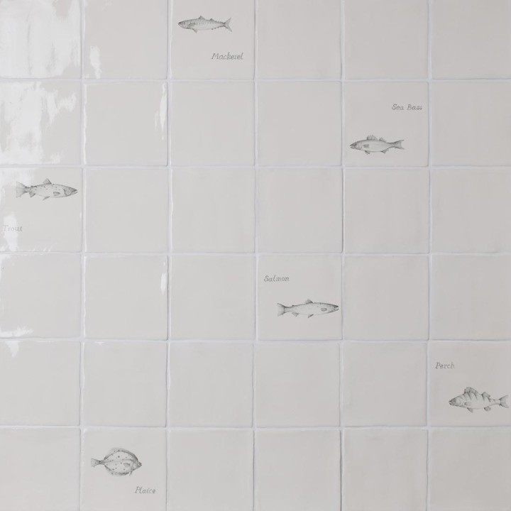 Wall of antique white tiles and fish tiles hand painted with fish motifs with white grout