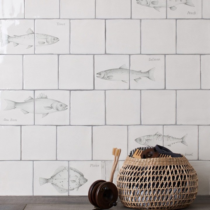Wall of antique white tiles and pairs of fish tiles hand painted with fish motifs with medium grey grout