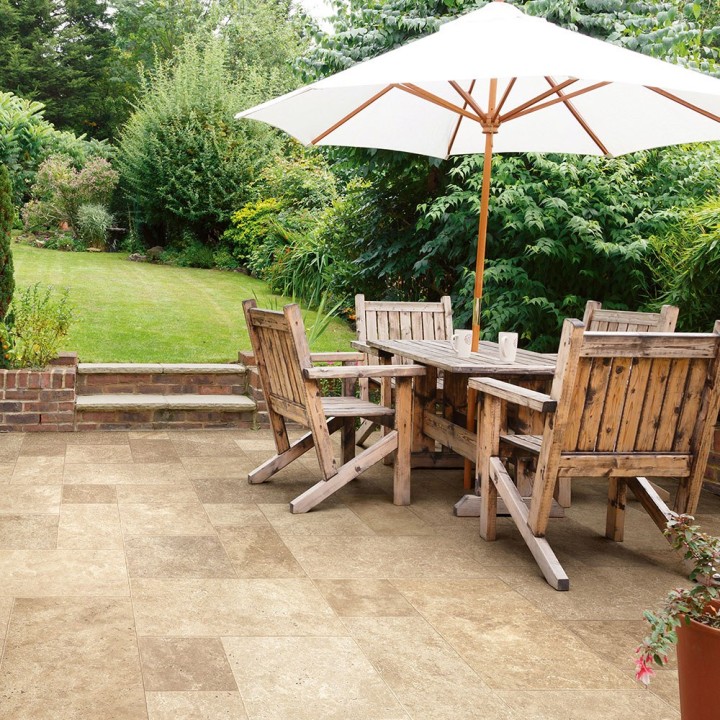 Garden patio with a french limestone floor, wood patio furniture and green lawn in the background