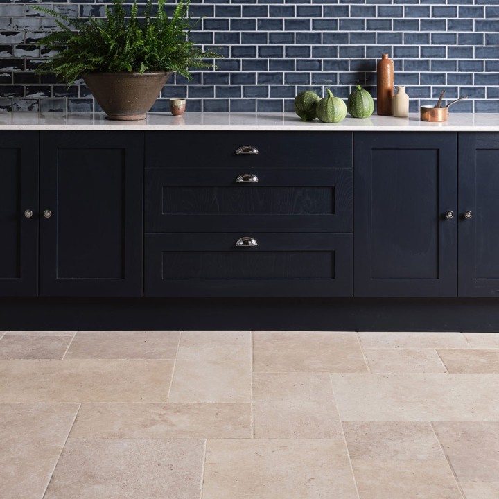 Limestone floor tiles paired with a black kitchen cabinet with blue metro wall tiles