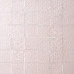 Wall of blush pink handmade square tiles with white grout