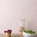 Wall of blush pink handmade square tiles with hand piped patterns with white grout behind home accessories