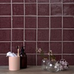 Wall of handmade burgundy red square tiles with grey grout behind bathroom accessories