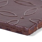 Corner of artisan rustic burgundy square tile with flower pattern piped on top