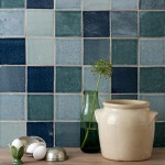 Wall of four shades of rustic blue square tiles with beige grout behind home accessories