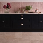 Handmade rose pink square tiles behind navy kitchen cabinets with kitchen accessories on top and a french limestone floor.
