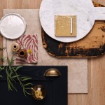 Flatlay of a yellow square tile on top of oak and stone effect floor tiles against a navy cupboard door